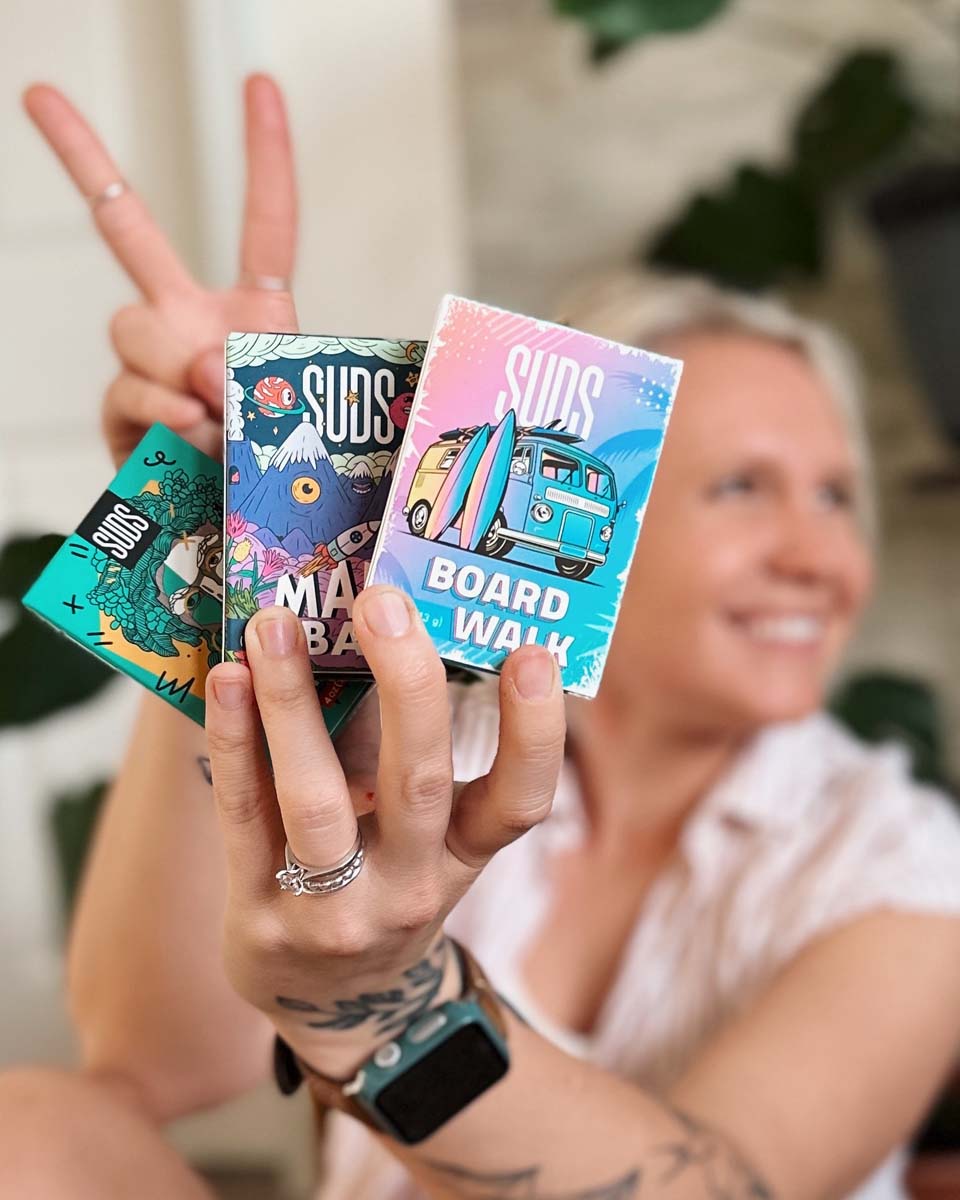 Woman holding three soaps and smiling at camera 